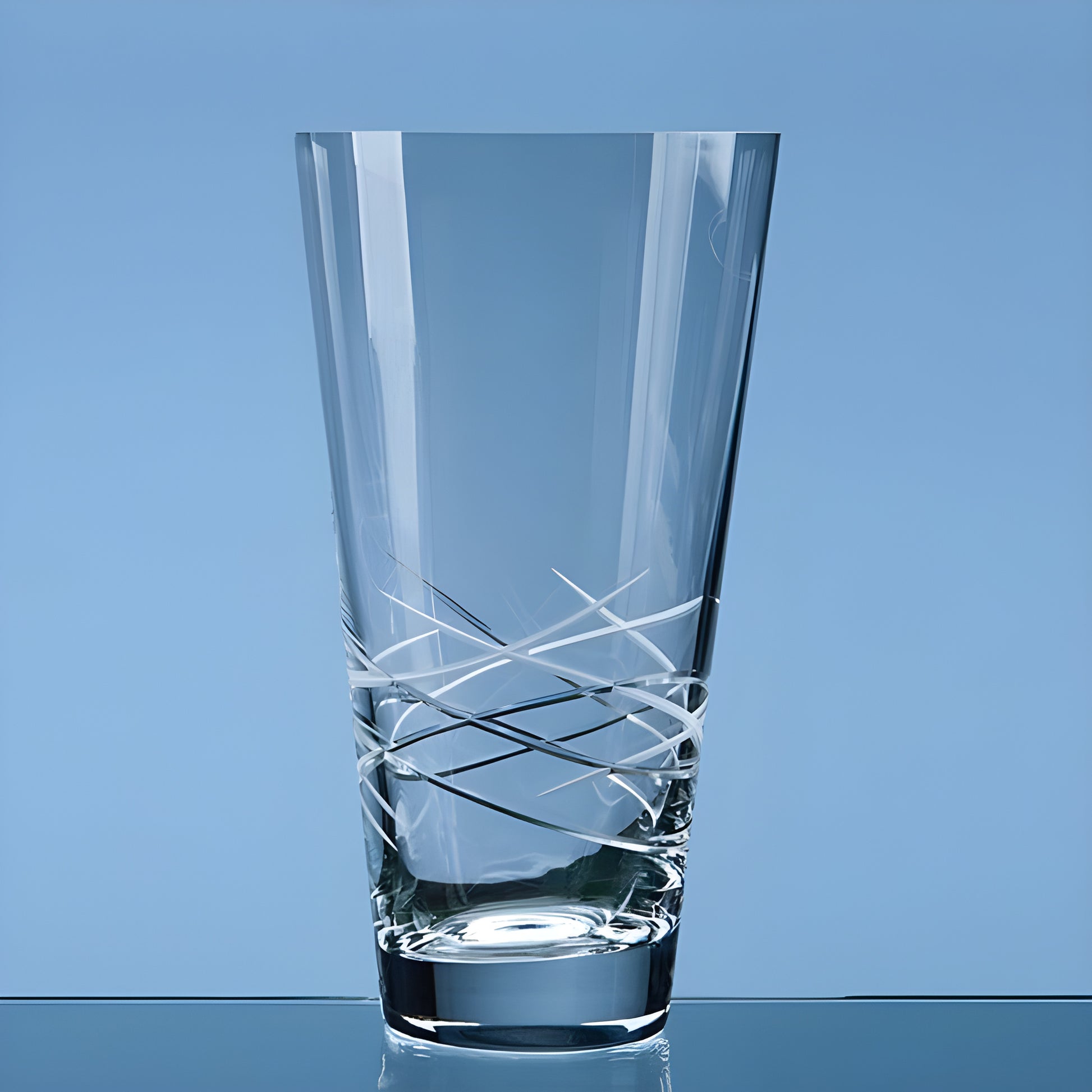 Crystal clear conical vase with geometric design on a blue background.