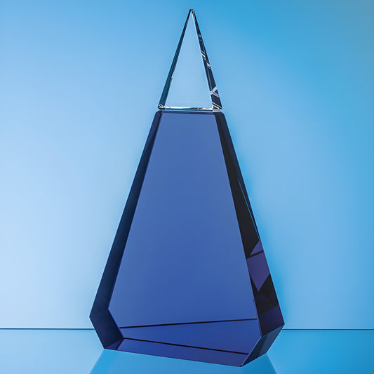 Cobalt blue and clear optical crystal prism award with geometric design on blue background.