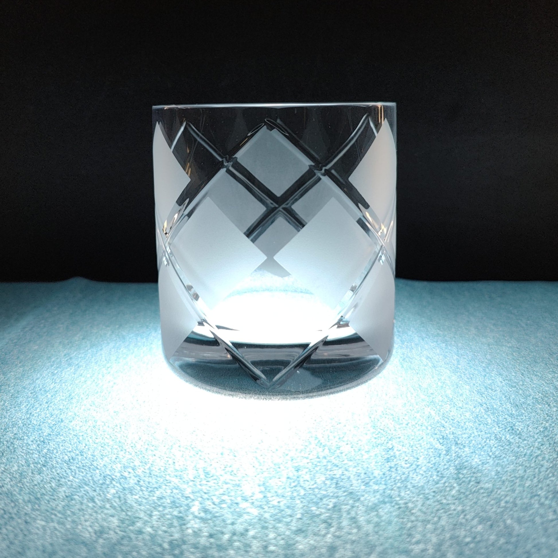 Cut glass tumbler with argyle pattern on blue table surface.
