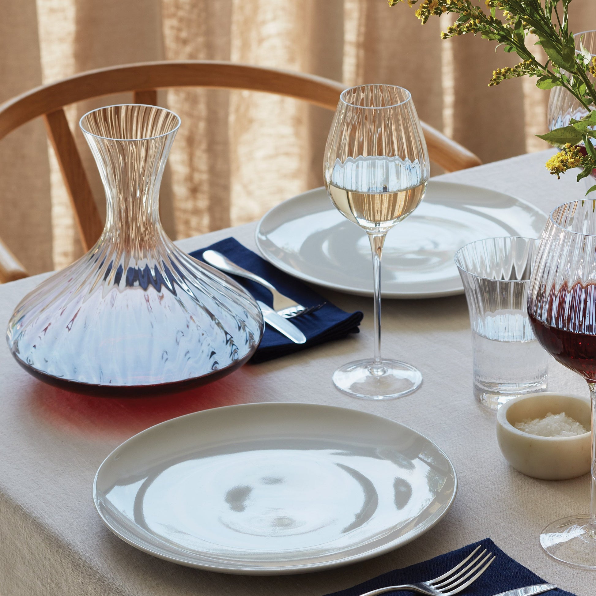 Decorative table setting with carafe, wine glasses, and floral centerpiece.