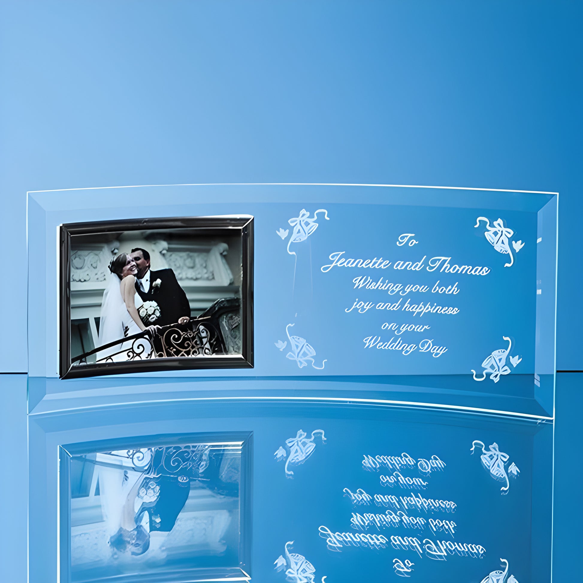 Engraved bevelled glass crescent frame with wedding photo and message on blue background.
