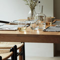 Modern dining setup with stemless glasses on a wooden table and purple flowers in a vase.