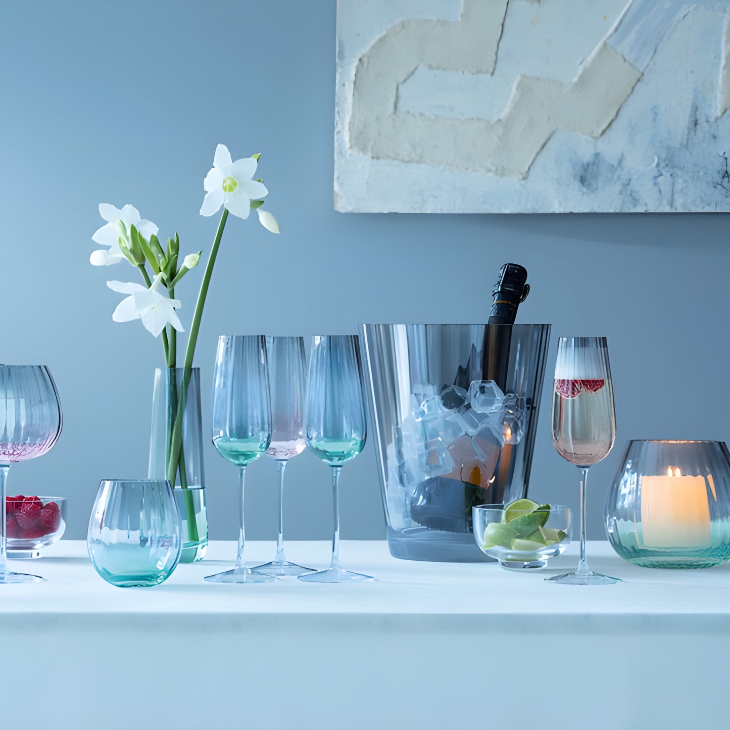 Elegant table setting with dusk balloon goblets, wine chiller, candle, and daffodils.