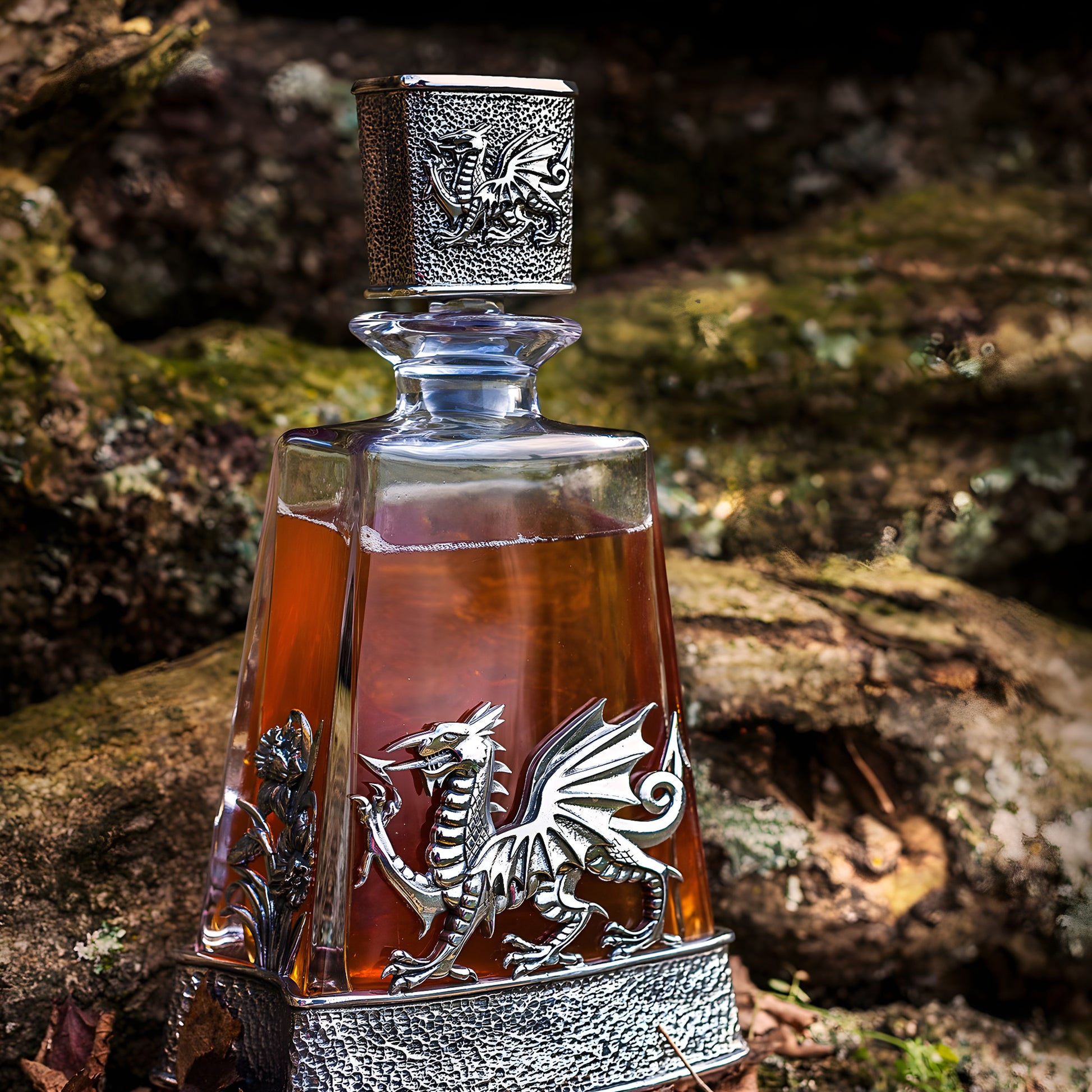 Ornate glass and pewter decanter with Welsh dragon and daffodil design in a forest setting.