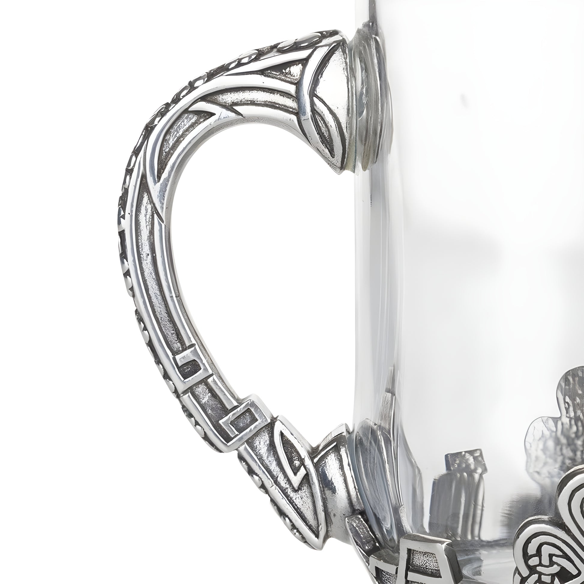 Closeup of glass and pewter Irish tankard with Celtic design handle.