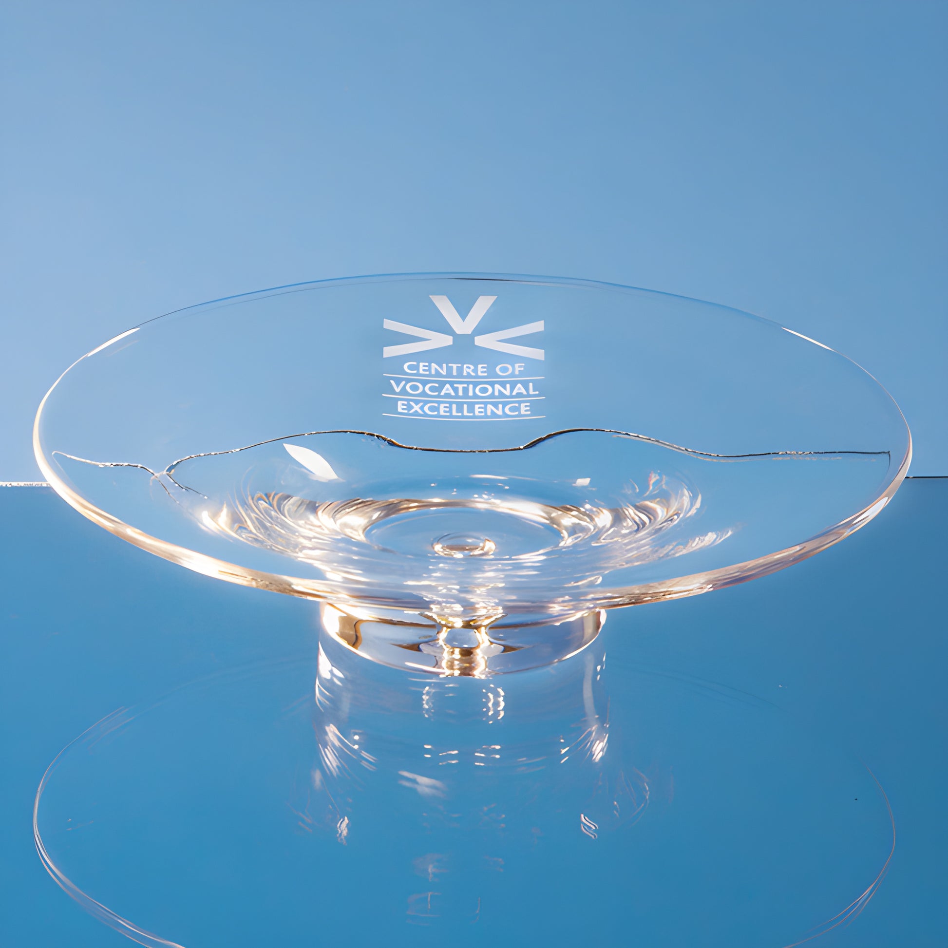 Clear glass bubble base shallow bowl with inscription on blue background.