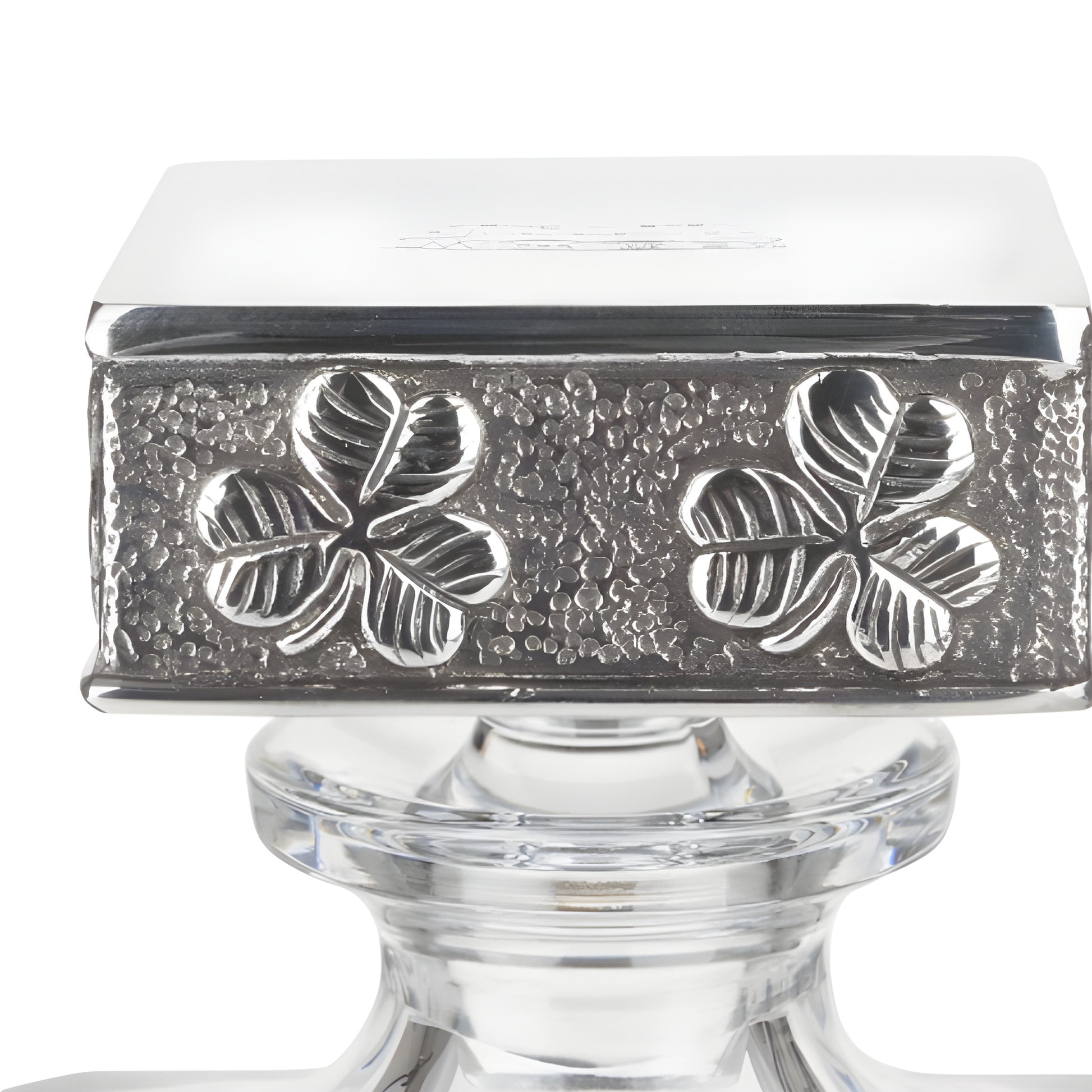 Silver cap with four-leaf clover engraving on glass decanter.
