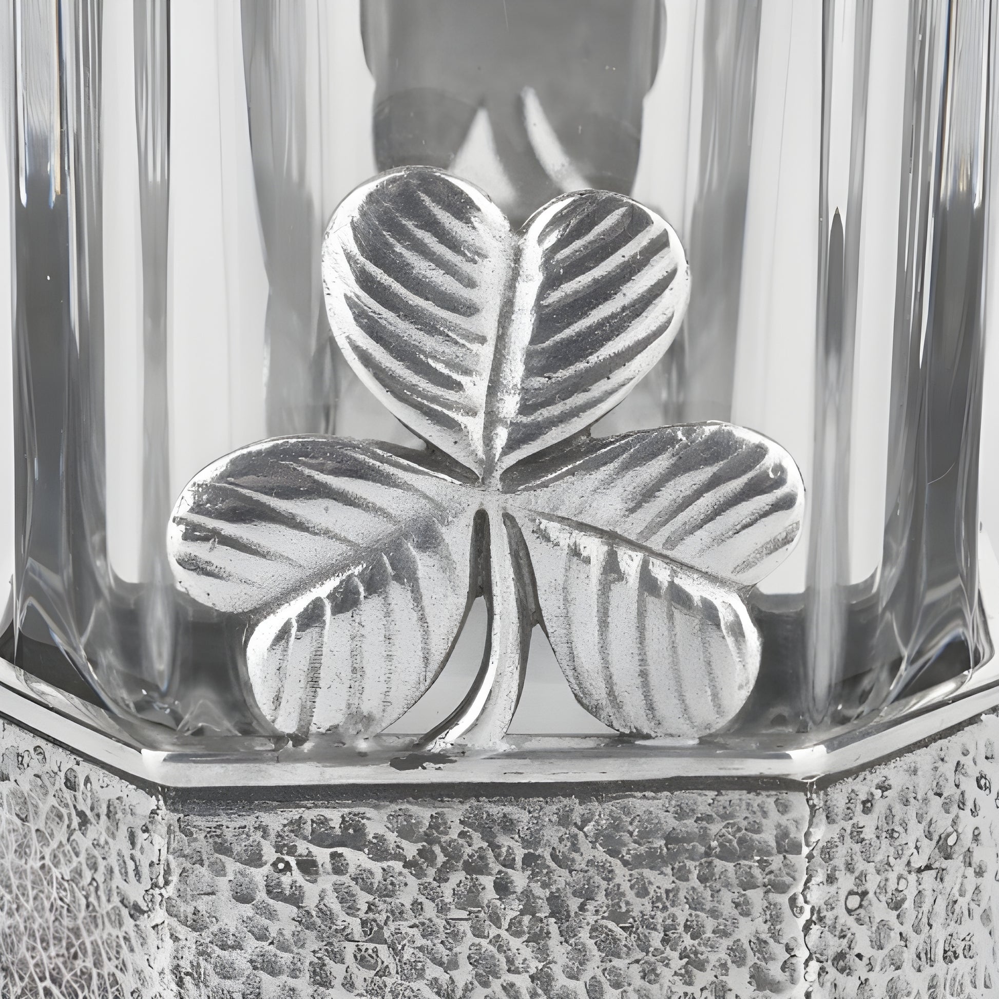 Close-up of a silver shamrock design on a glass decanter base.