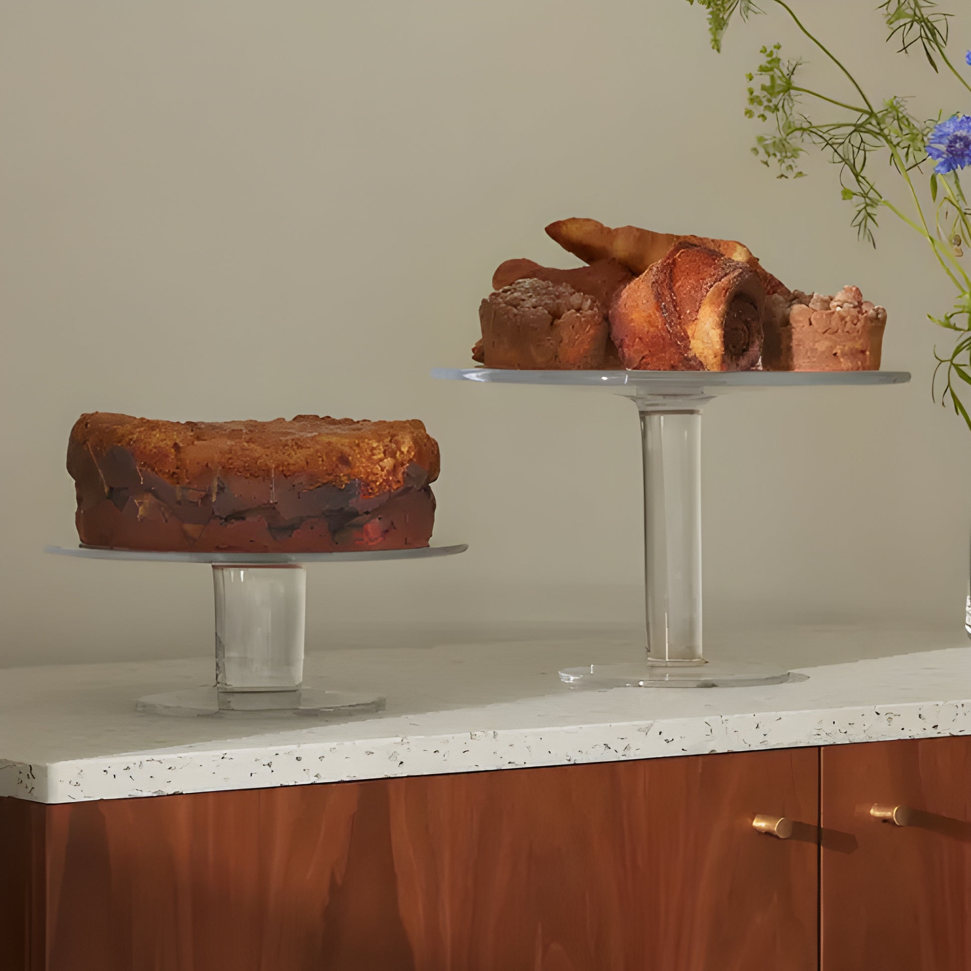 Glass cake stands with assorted pastries on a wooden cabinet