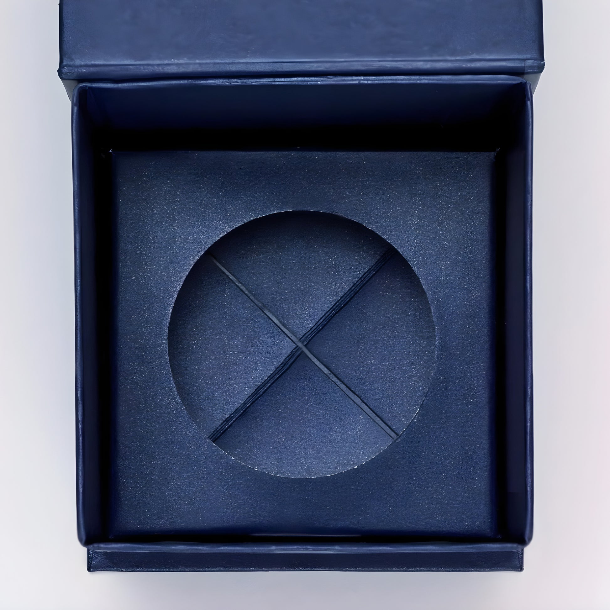 Open navy blue gift box with a textured insert for a small item.