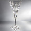 Crystal wine glass with engraved round shapes on a reflective surface.