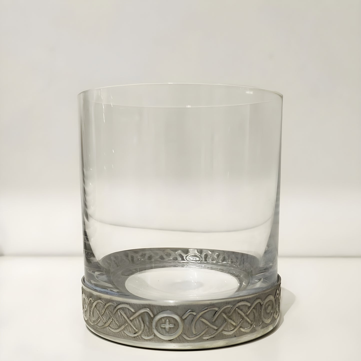 Whisky glass with a pewter base featuring a Celtic etched spiral design.