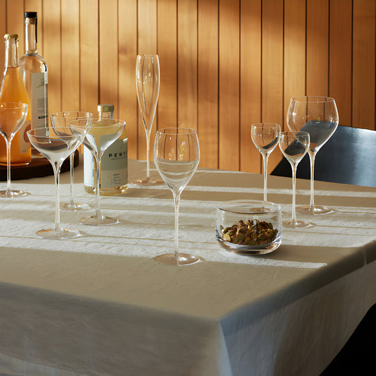 Elegant table setting with various glassware and bottles under warm lighting.
