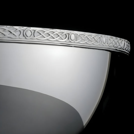 Close-up of a silver-plated Celtic quaich with intricate engraved design.