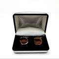 Silver round cufflinks displayed in a chrome box with black interior