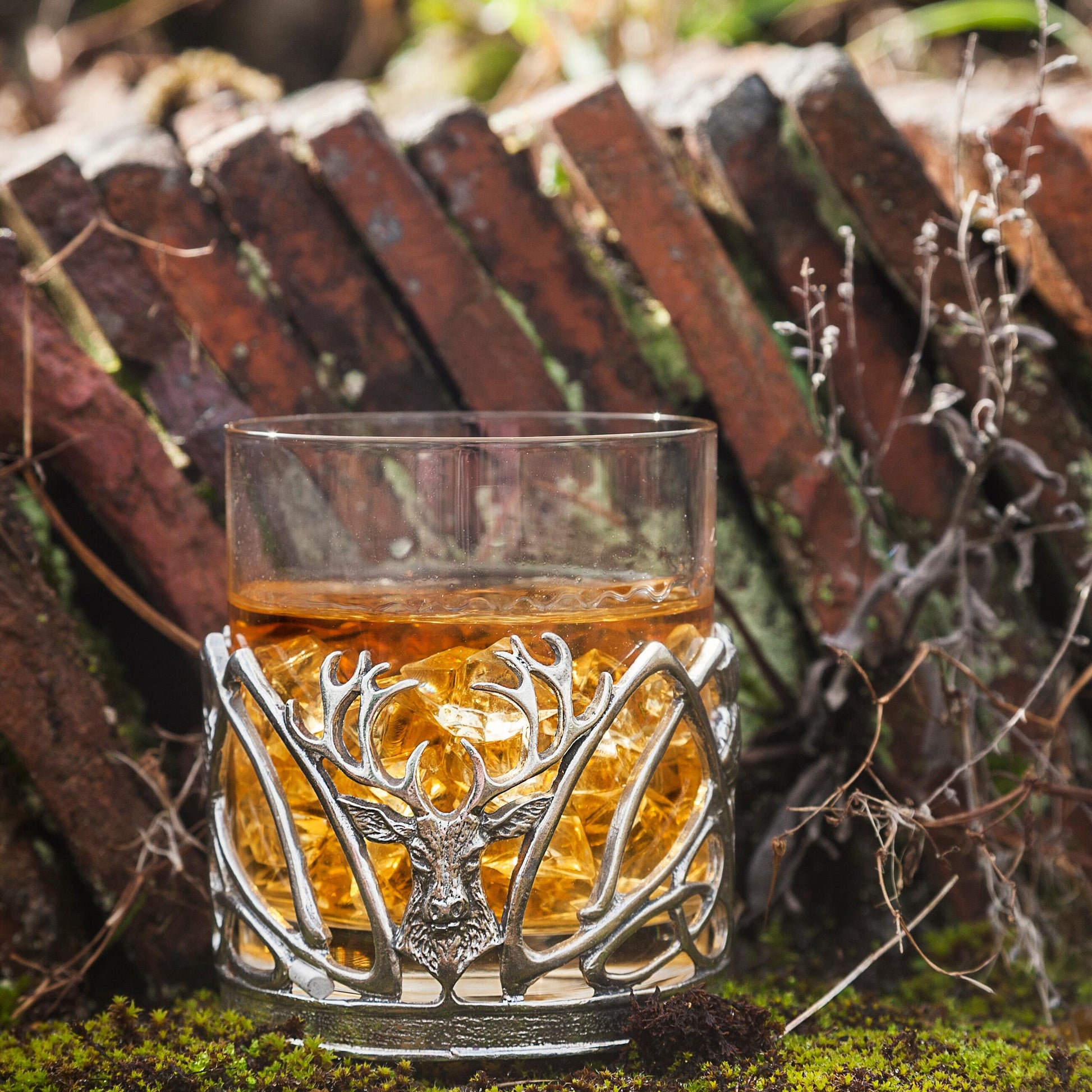 Whisky in an antler-design glass with ice and a rustic background.