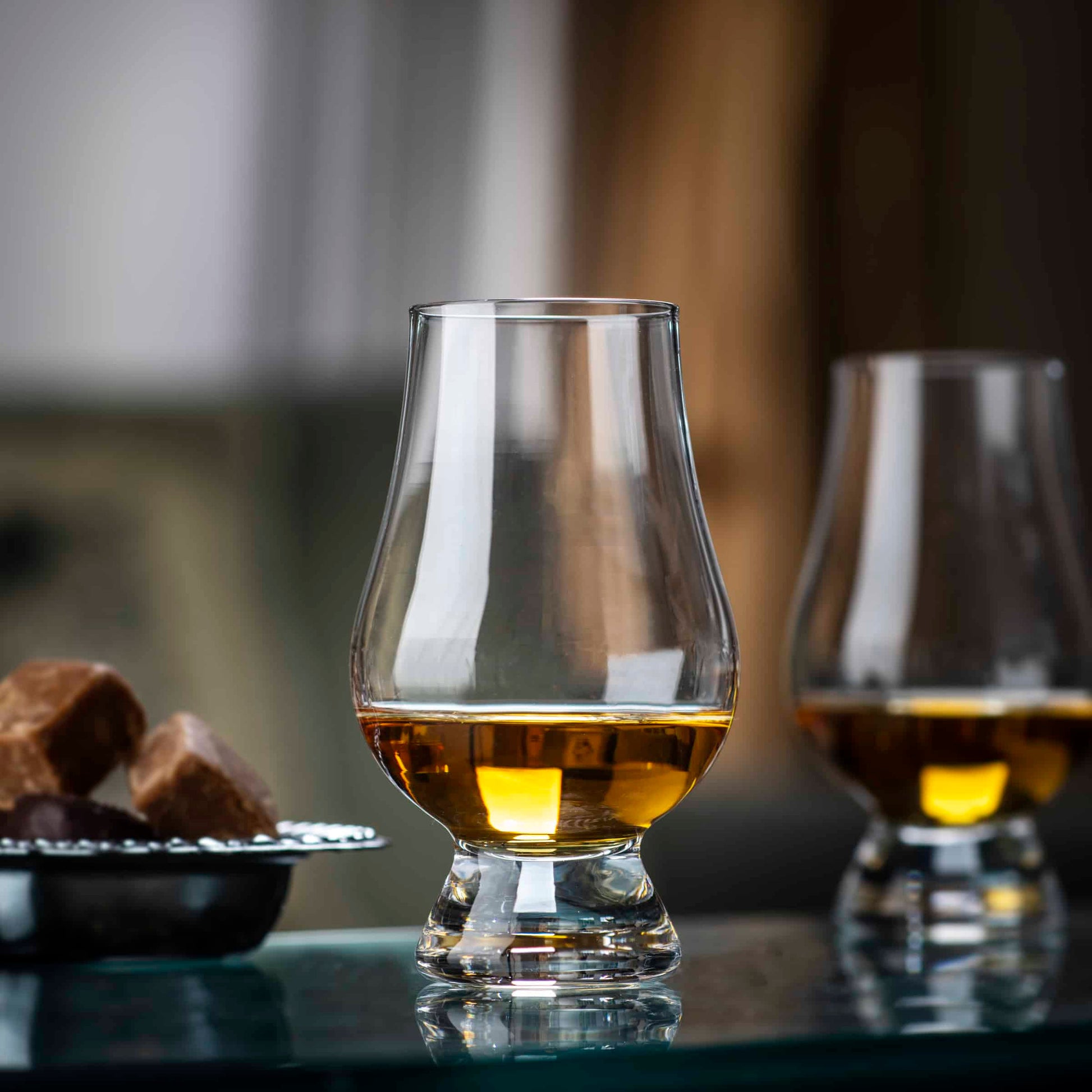 Glencairn whisky tasting glass beside Scotch whisky and chocolates.