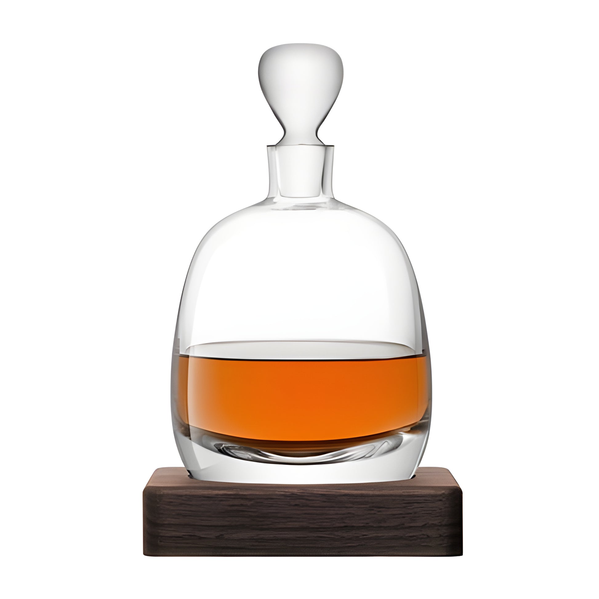 Glass whisky decanter filled with amber whisky on a wooden stand.