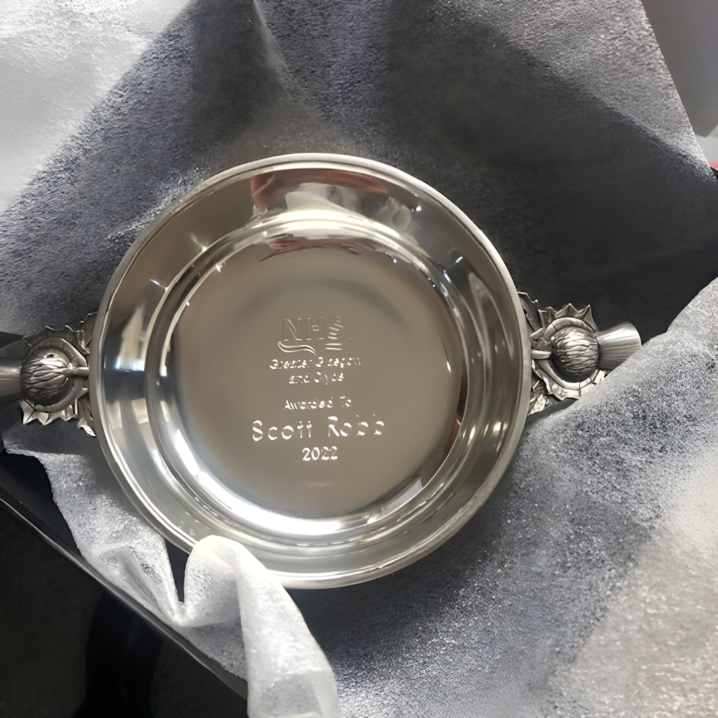 Engraved traditional pewter quaich with thistle handles in decorative box.