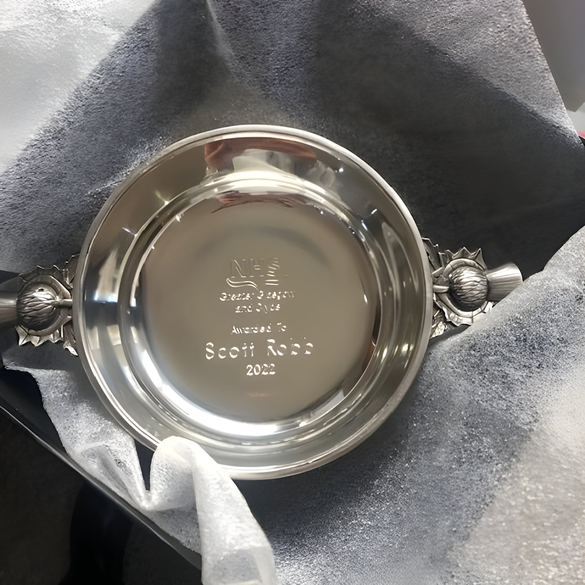 Engraved traditional pewter quaich with thistle handles in decorative box.