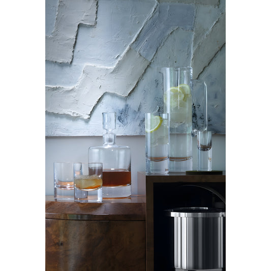 Whisky decanter set with glasses and lemon water on wooden shelf.