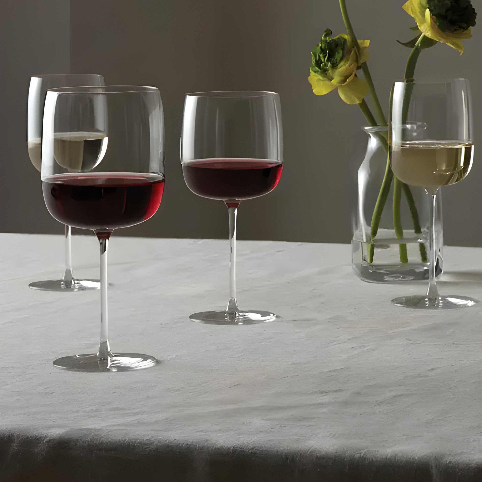 Four wine glasses with red and white wine on table with flowers
