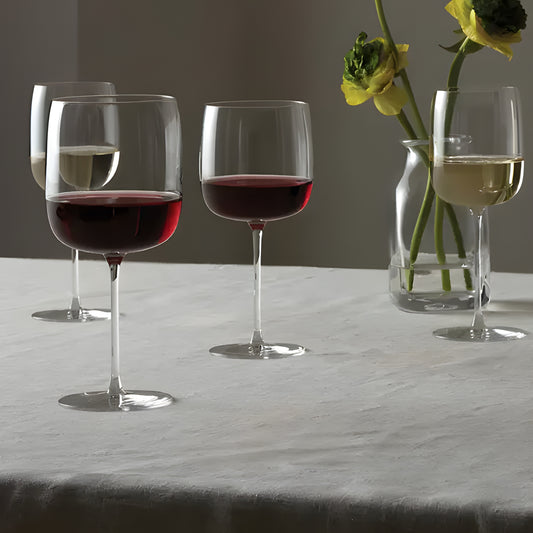 Four wine glasses with red and white wine on table with flowers