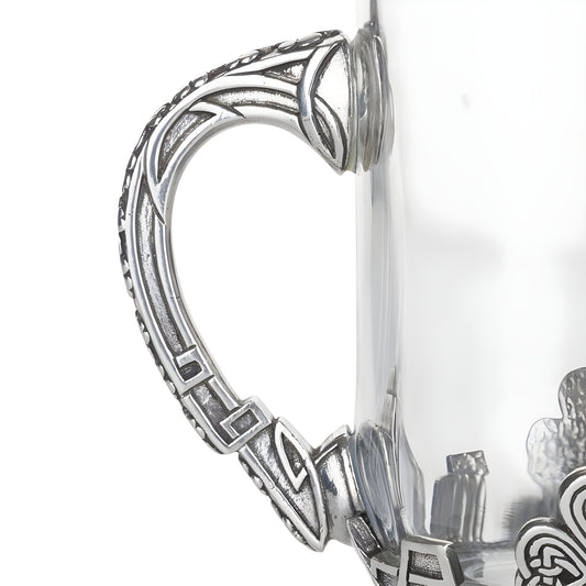 Closeup of glass and pewter Irish tankard with Celtic design handle.