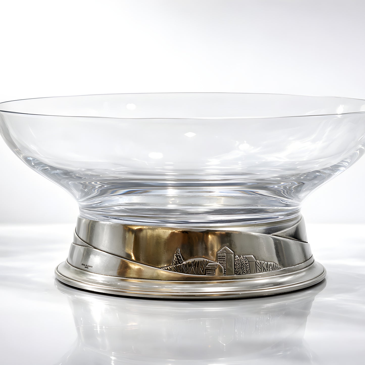 Clear glass bowl with decorative pewter base on white surface.