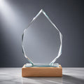 Glass iceberg-shaped award with wooden base on marble surface.