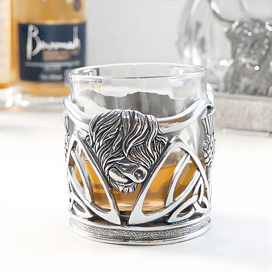 Pewter whisky glass with highland cow design and whisky inside.
