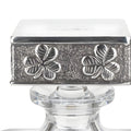 Silver cap with four-leaf clover engraving on glass decanter.