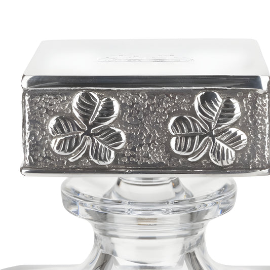 Silver cap with four-leaf clover engraving on glass decanter.