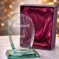 Jade crystal award with red box on table.