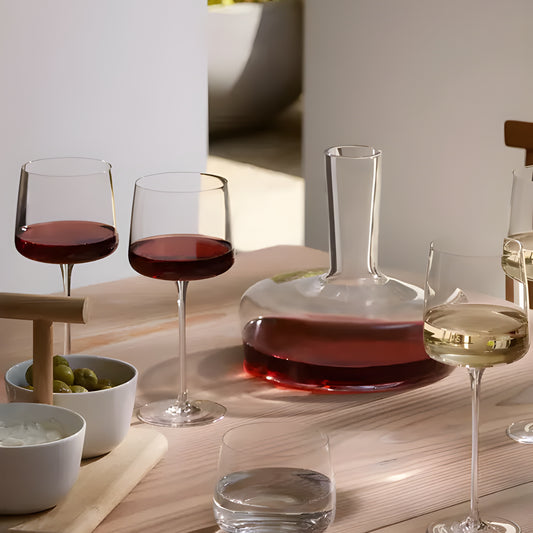 Red and white wine glasses with a decanter on a wooden table