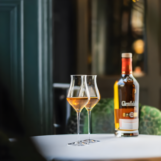 Pair of 190ml whisky glasses on a table with a whisky bottle in the background.