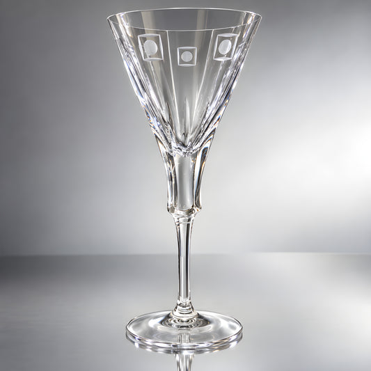 Crystal wine glass with engraved round shapes on a reflective surface.