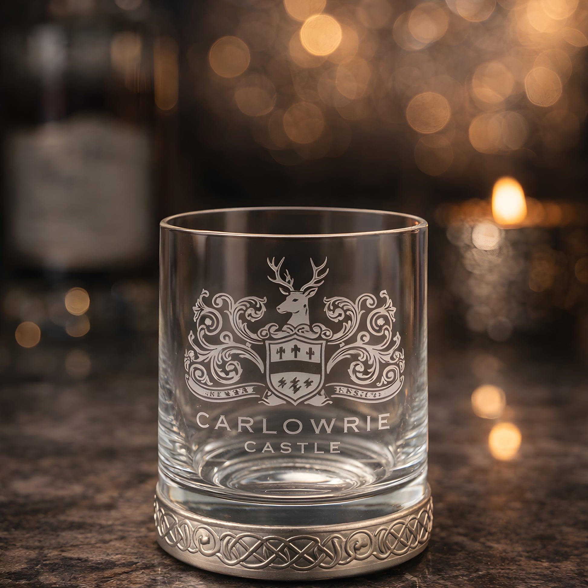 Engraved whisky glass with pewter base featuring Carlowrie Castle crest on marble surface.