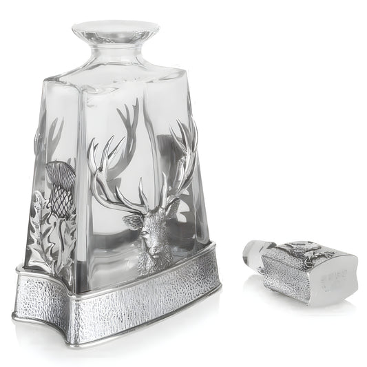 Crystal whisky decanter with stag and thistle design on a reflective surface.