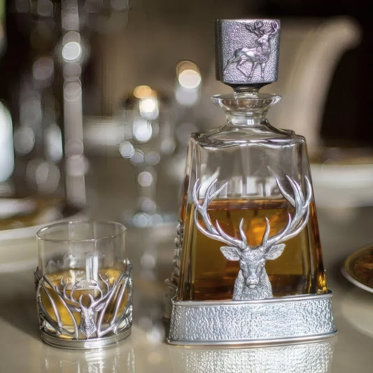 Elegant whisky decanter and glass with silver stag decoration.