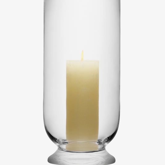 Glass hurricane candle holder with a lit white pillar candle.