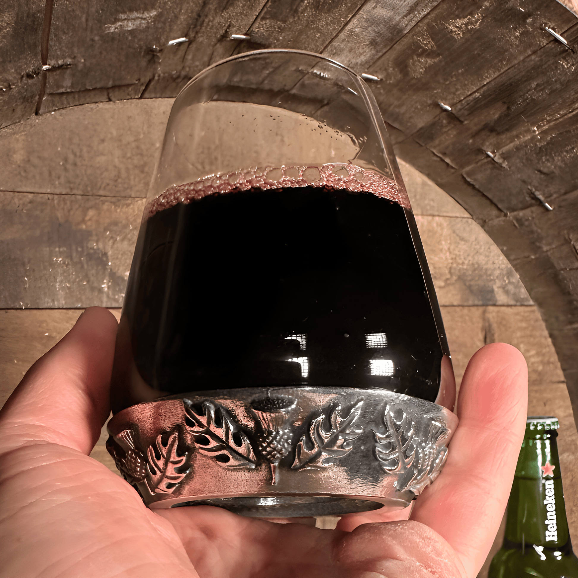 Hand holding a thistle-themed whisky glass filled with red wine.